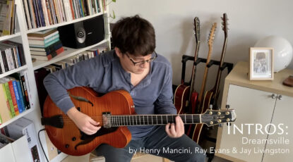 Matt in his naturally lit living room in the morning in front of the bookshelf with his Sadowsky Jim Hall guitar