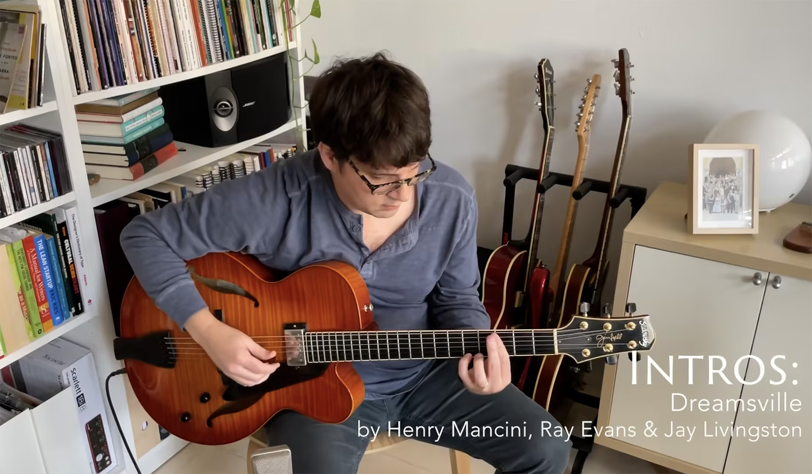 Matt in his naturally lit living room in the morning in front of the bookshelf with his Sadowsky Jim Hall guitar